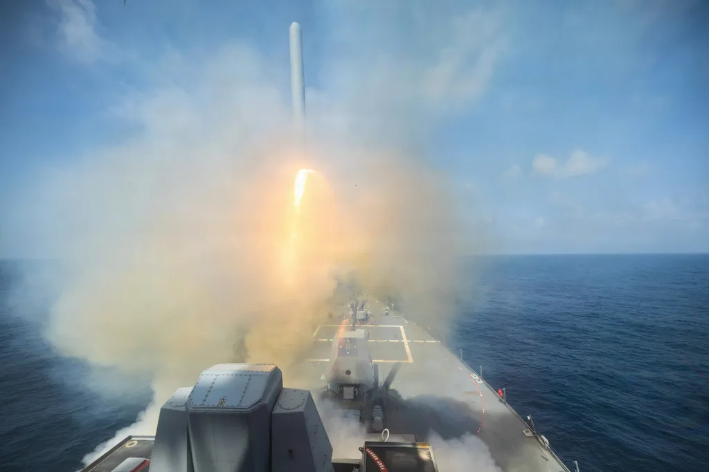 Dust clouds of gray and a bright flame of yellow tee off the Arleigh Burke-class guided-missile destroyer USS Spruance as it fires a Tomahawk Land Attack Missile in support of Operation Epic Fury.