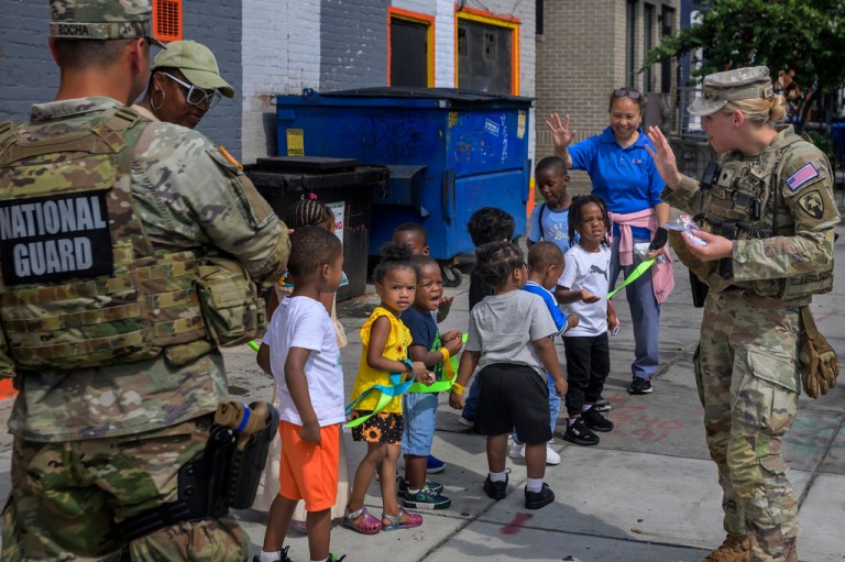 Members of the Iowa National Guard talk with a group of children.