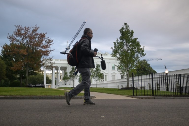 A CNN sound technician walks at the White House.