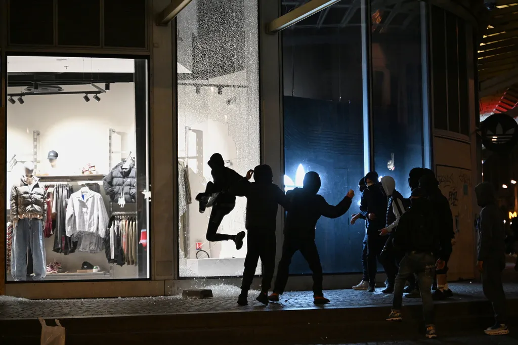Youths break a store window during clashes between protesters and police in Paris, Sunday.