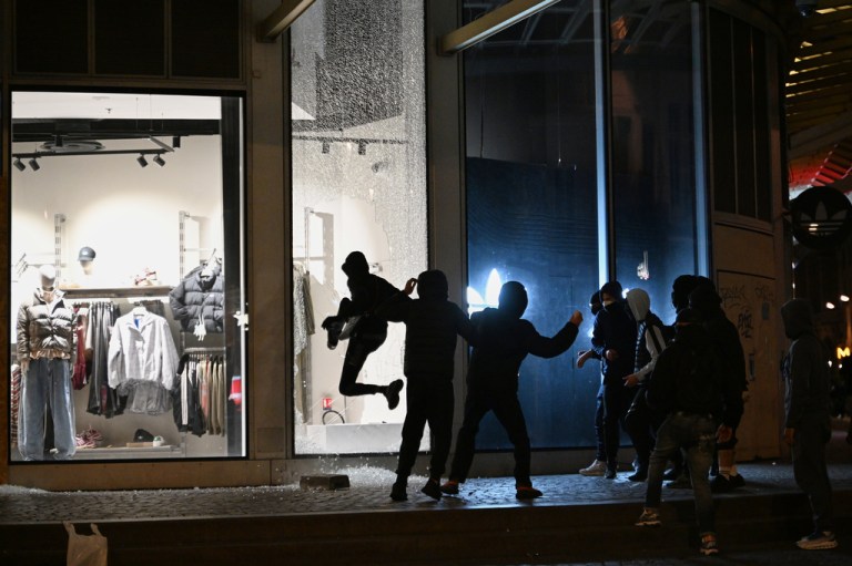 Youths break a store window during clashes between protesters and police in Paris, Sunday.