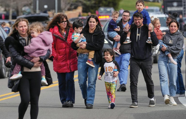 Law enforcement escorts families with children away from the Temple Israel synagogue on March 13 in West Bloomfield Township, Michigan, after Ayman Mohamad Ghazali rammed his truck filled with fireworks and jugs of flammable liquid through the front doors. (Photos by Paul Sancya/AP)