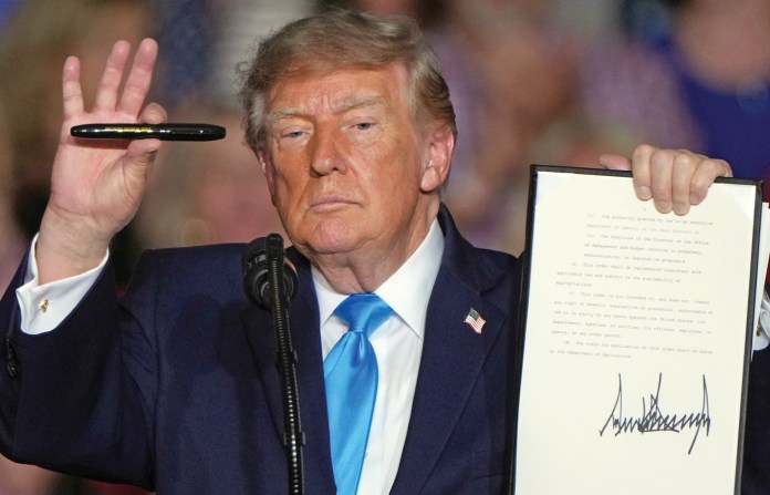 At a rally in Grand Island, Nebraska, President Donald Trump demonstrates his own version of Barack Obama’s ‘pen and phone’ method of governing, Oct. 5, 2026. (Charlie Riedel/AP)