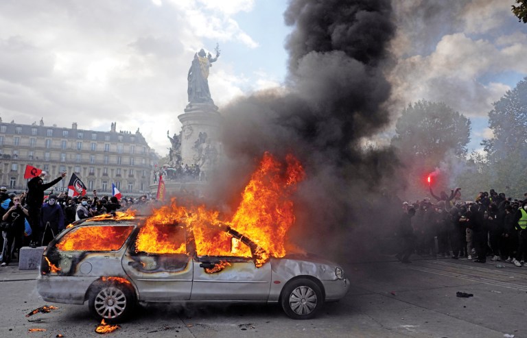 Rioters watch a car burn in Paris’s Republic Square. (Thibault Camus/AP)