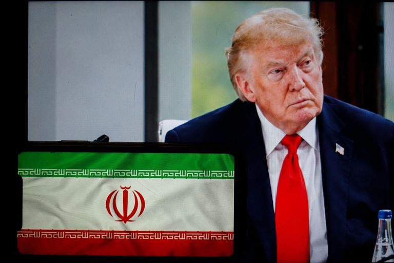 President Donald Trump is seen behind Iran flag.