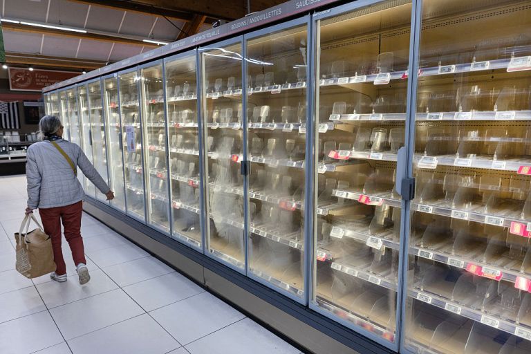 A woman walks past empty fresh-food refrigerators at an Intermarché supermarket in Névez, France, on Oct. 12, 2026, following a cyberattack affecting French supermarket chains.