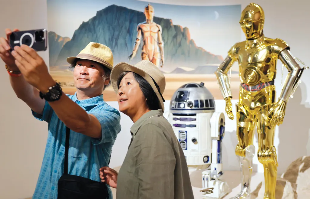 People take a photo with R2-D2 and C-3P0 while visiting the "Star Wars in Motion" exhibit at the Lucas Museum of Narrative Art in Los Angeles, California. (Mario Tama/Getty Images)