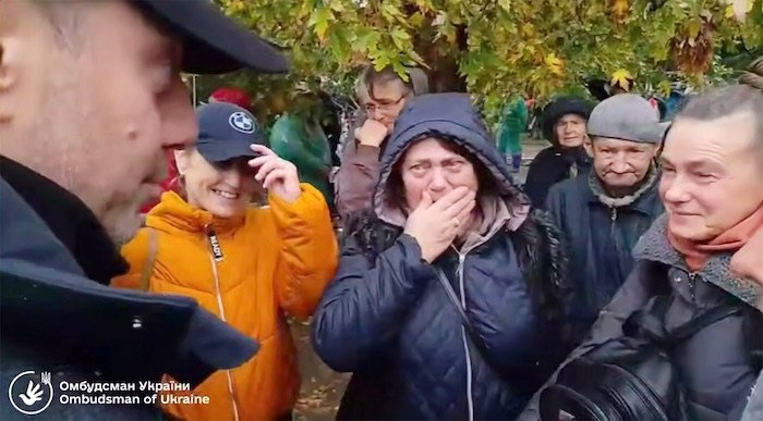 In this screenshot from a video provided by the Office of the Ombudsman of Ukraine, Ukraine's Ombudsman Dmytro Lubinets, left, speaks with residents of Oleshky during their evacuation to a safe area amid a local ceasefire connected to a humanitarian aid mission in Oleshky, Kherson region, Ukraine, Friday, Oct. 30, 2026.