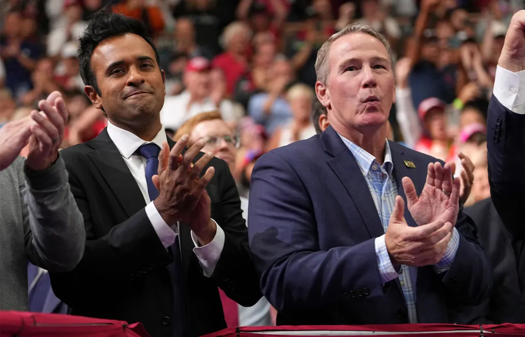 Ohio Republican gubernatorial candidate Vivek Ramaswamy, (left) and Sen. Jon Husted (R-OH) applaud as President Donald Trump speaks during a midterm election rally in Vandalia, Ohio, on Oct. 3. (Mark Schiefelbein/AP)