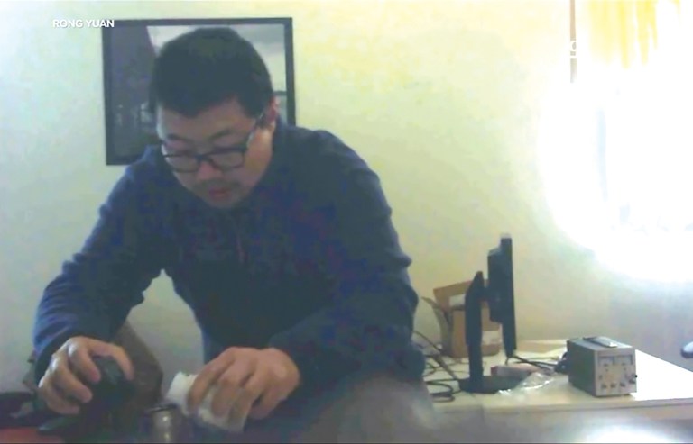 In this image taken from video, David Xu is seen pouring a substance into the water bottle of his co-worker, Rong Yuan. (Courtesy of Rong Yuan)