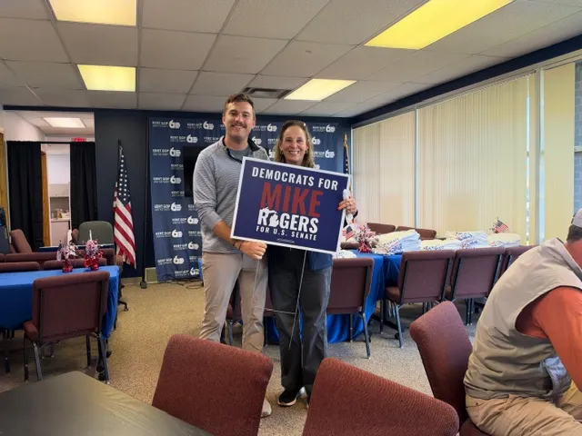 Jake Frievalt holds a 'Democrats for Rogers' yard sign.